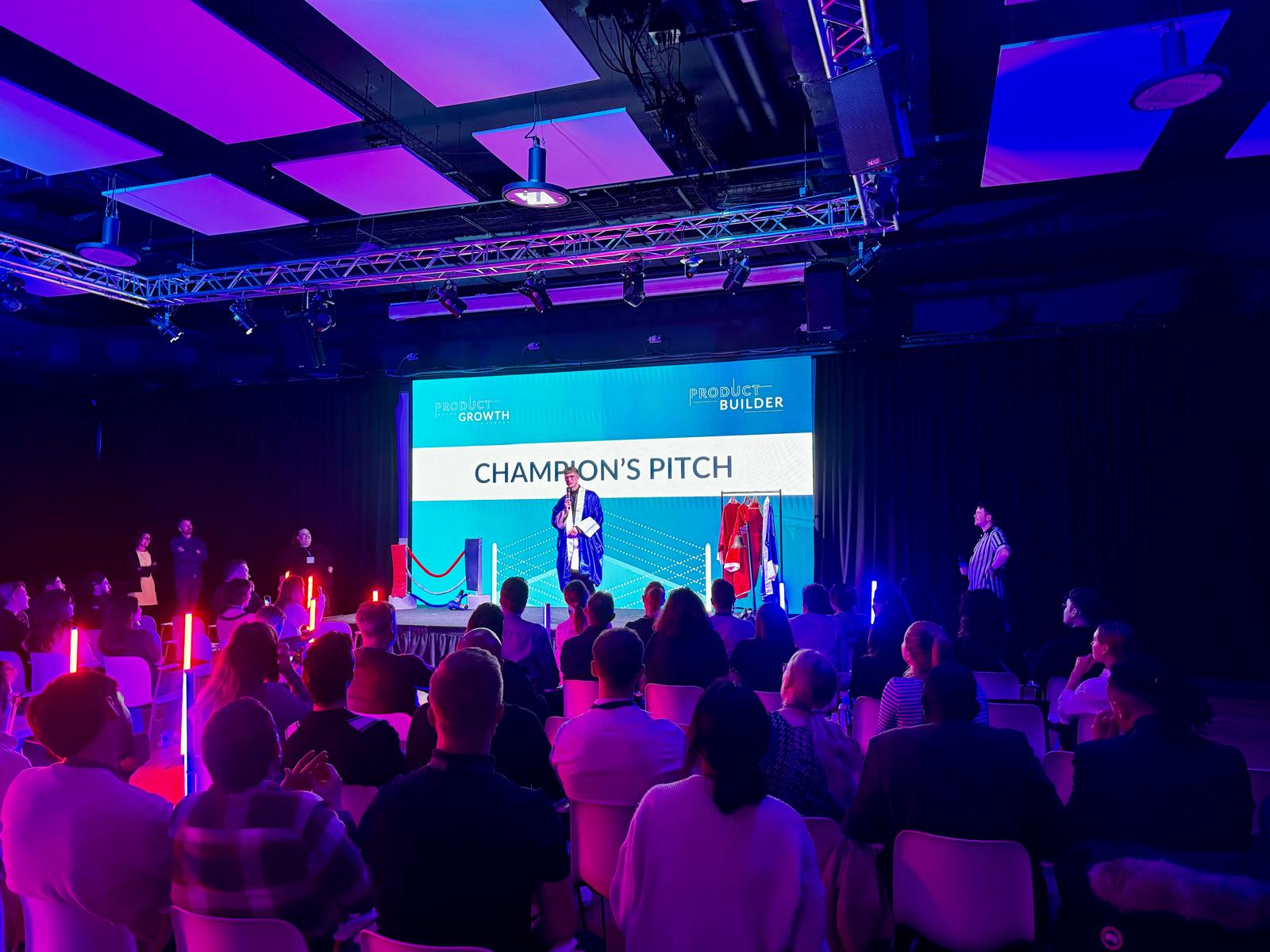 Mark on stage at Champion’s Pitch, speaking to a seated audience