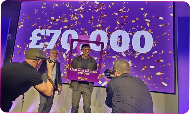 Mark celebrating first place at an Accelerator pitch event, holding a winner’s frame